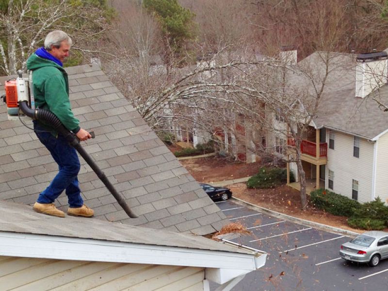 Gutter cleaning technician on roof.